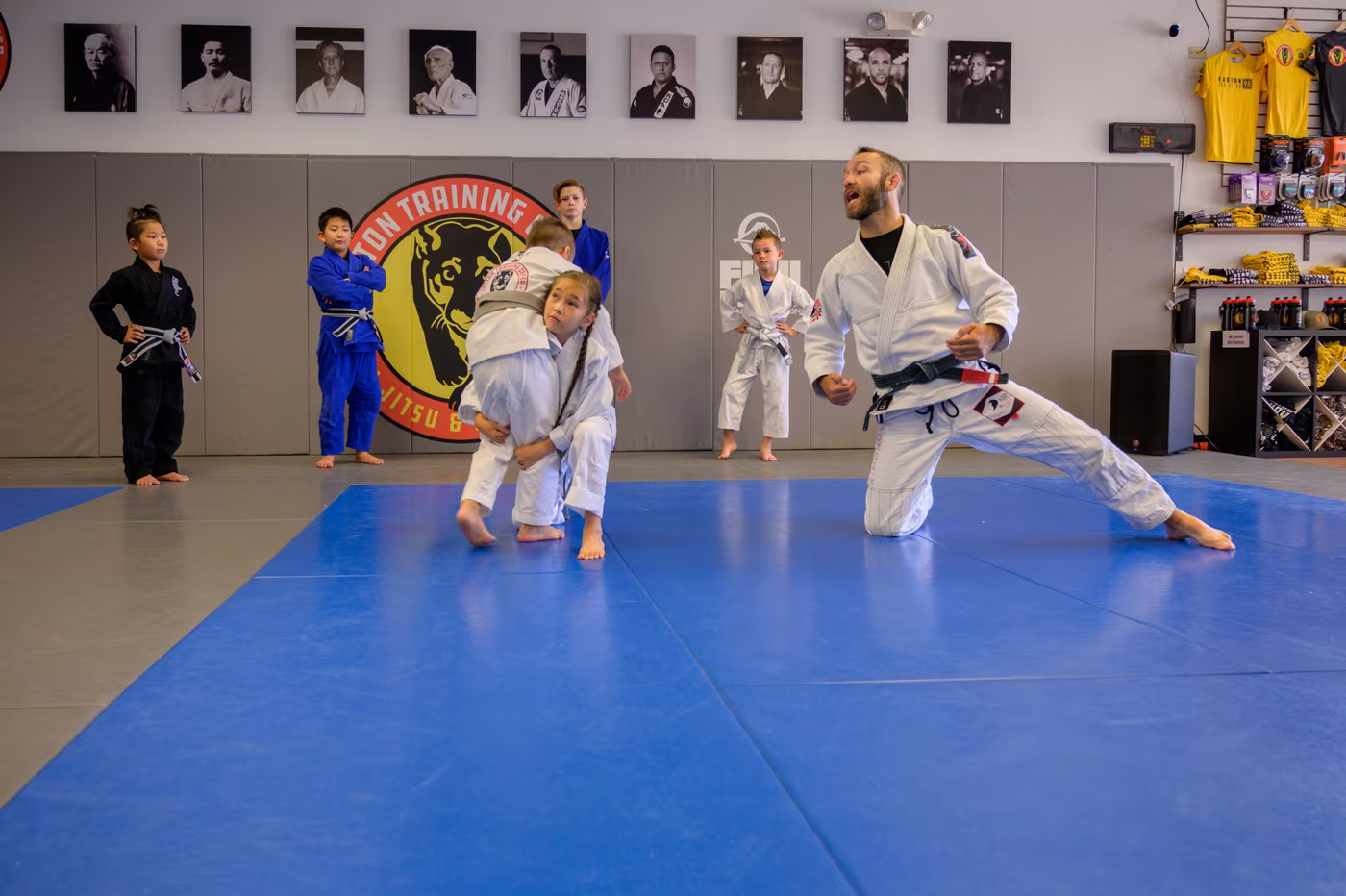 Two Tigers drilling a takedown while their coach calls the technique