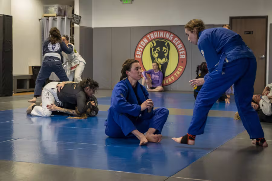 Women in gis resetting between rounds in Easton’s women’s jiu-jitsu class