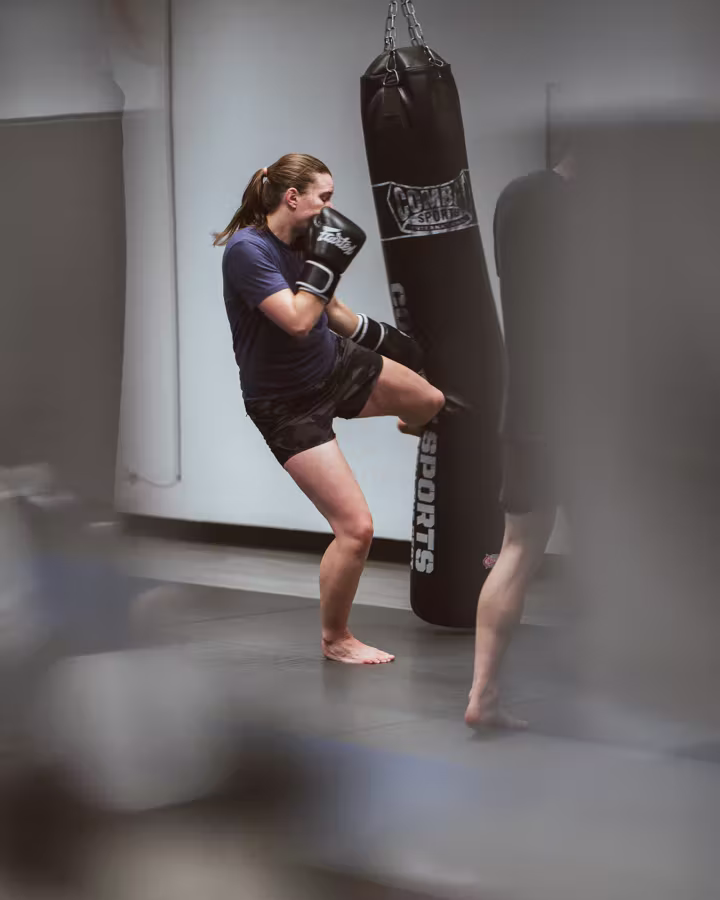 A woman drilling knees on the heavy bag in an Easton kickboxing class