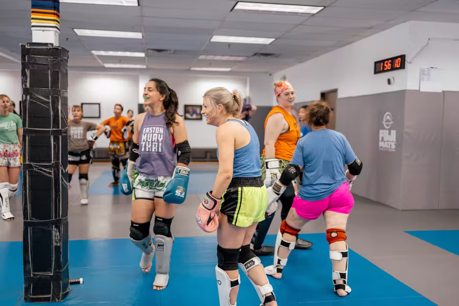 Women in gloves and shin guards between rounds in Easton’s women’s Muay Thai class
