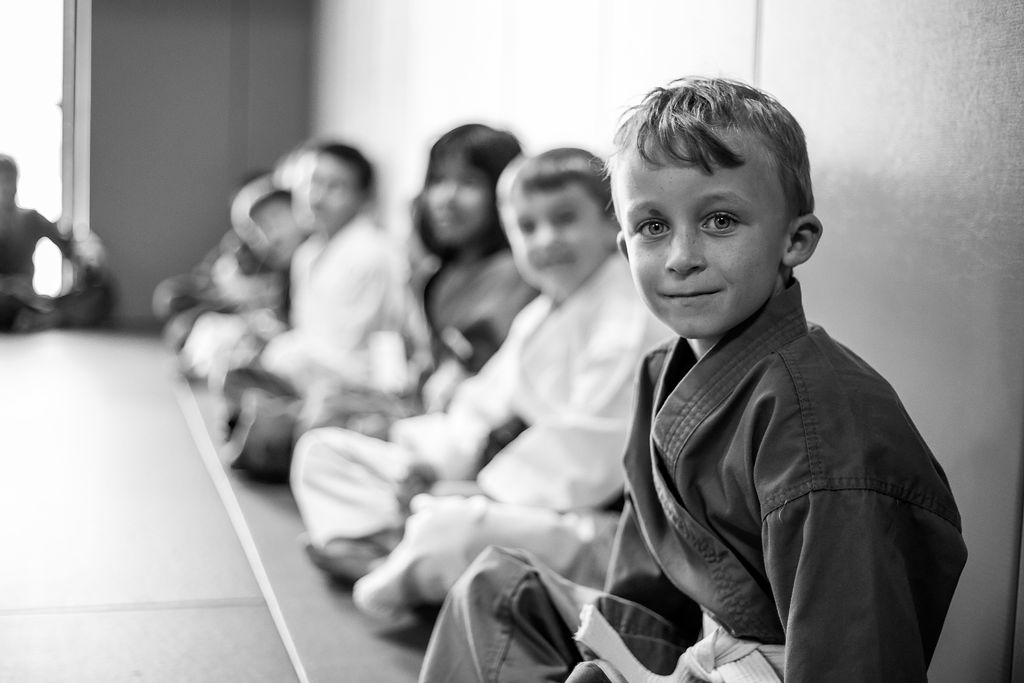 Kids smile as they sit in a line at Easton Training Center BJJ class