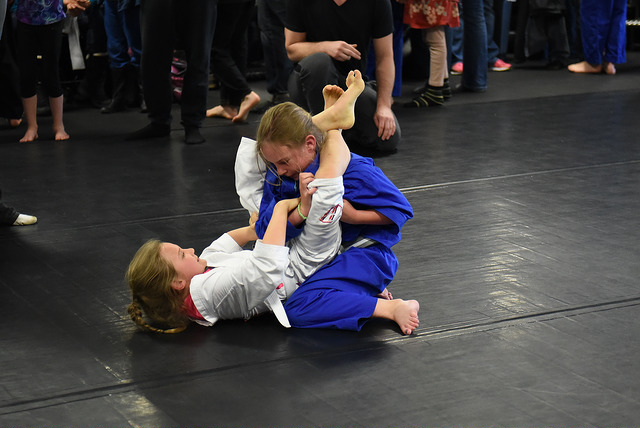 A girl sets up a triangle choke on another girl in a BJJ match