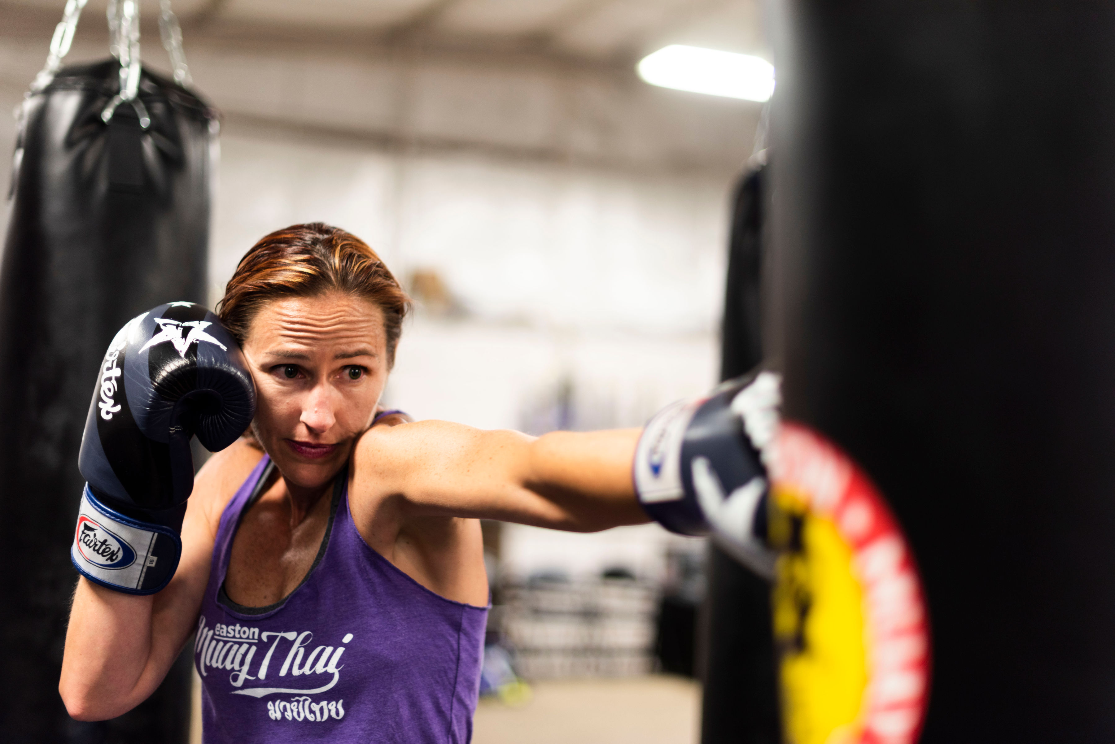 A woman punching a kickboxing heavy bag
