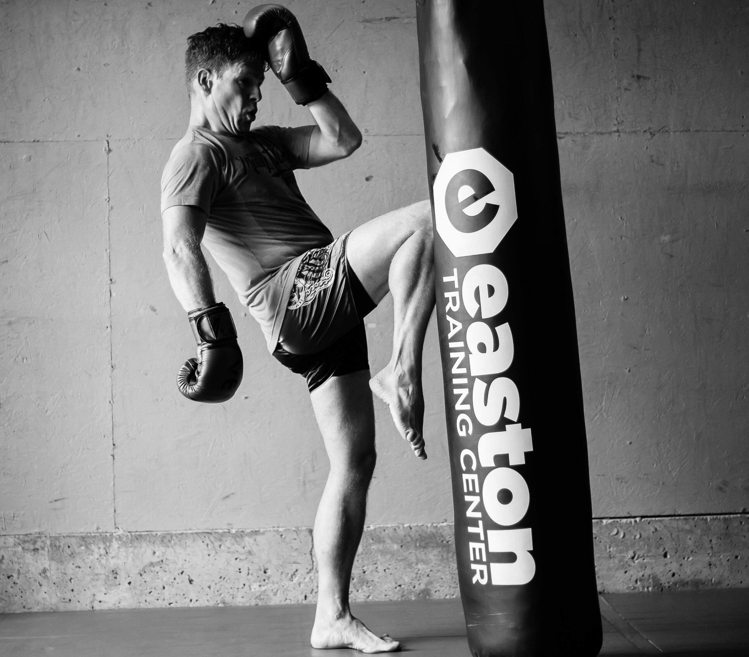 a man knees a punching bag labeled with the words "Easton Training Center" in a kickboxing class