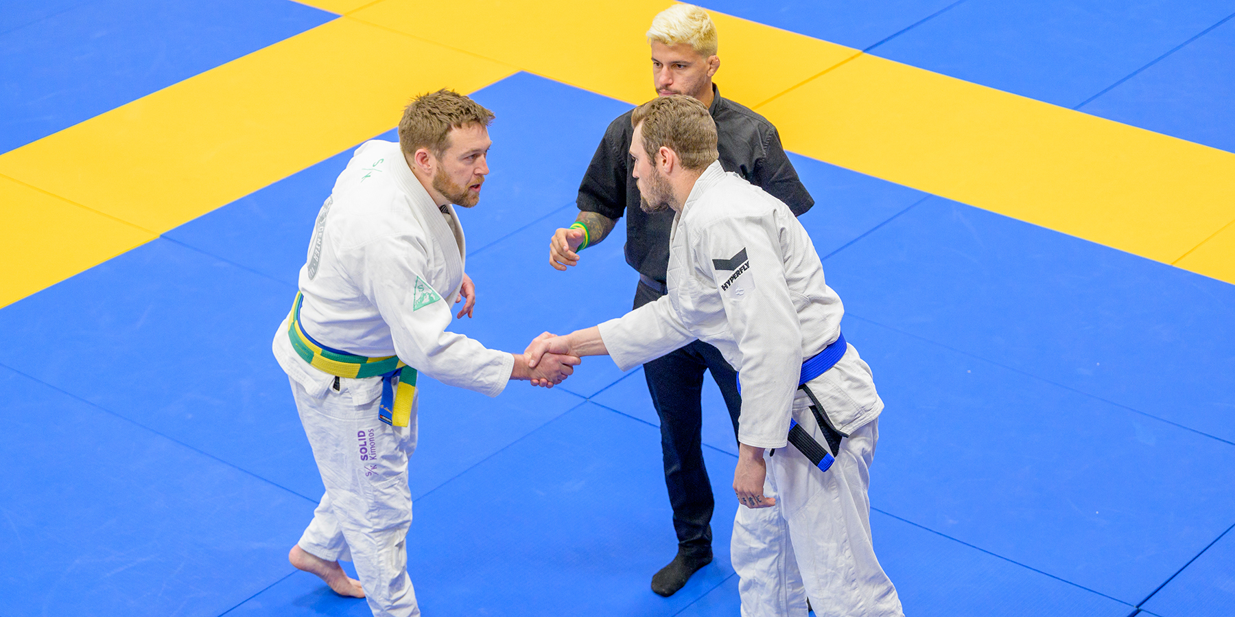 An image of two Brazilian Jiu-Jitsu competitors shaking hands before their match at the IBJJF Denver Open starts.