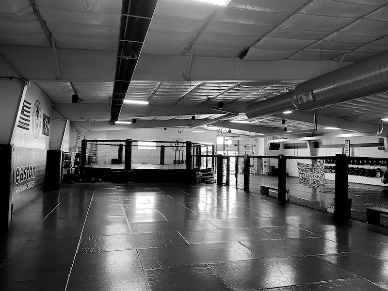 An image of the mat space used for Brazilian Jiu Jitsu classes and the MMA cage at Easton Training Center in Denver, Colorado.