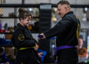A teen Jiu Jitsu student receives her adult blue belt