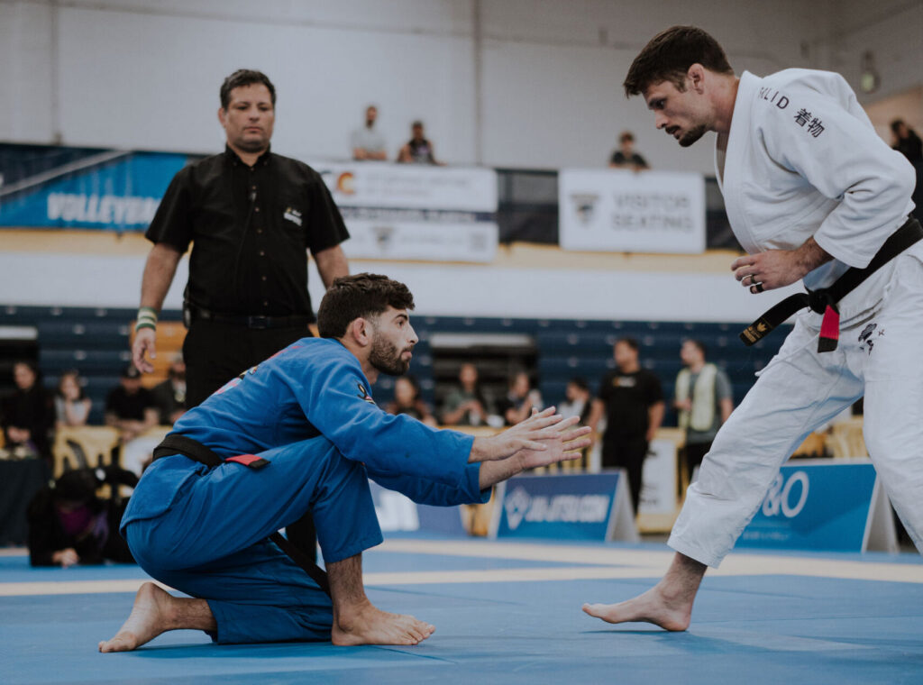 Professor Carlos Espinosa wears a white gi and faces off with an opponent at the IBJJF Denver Open 
