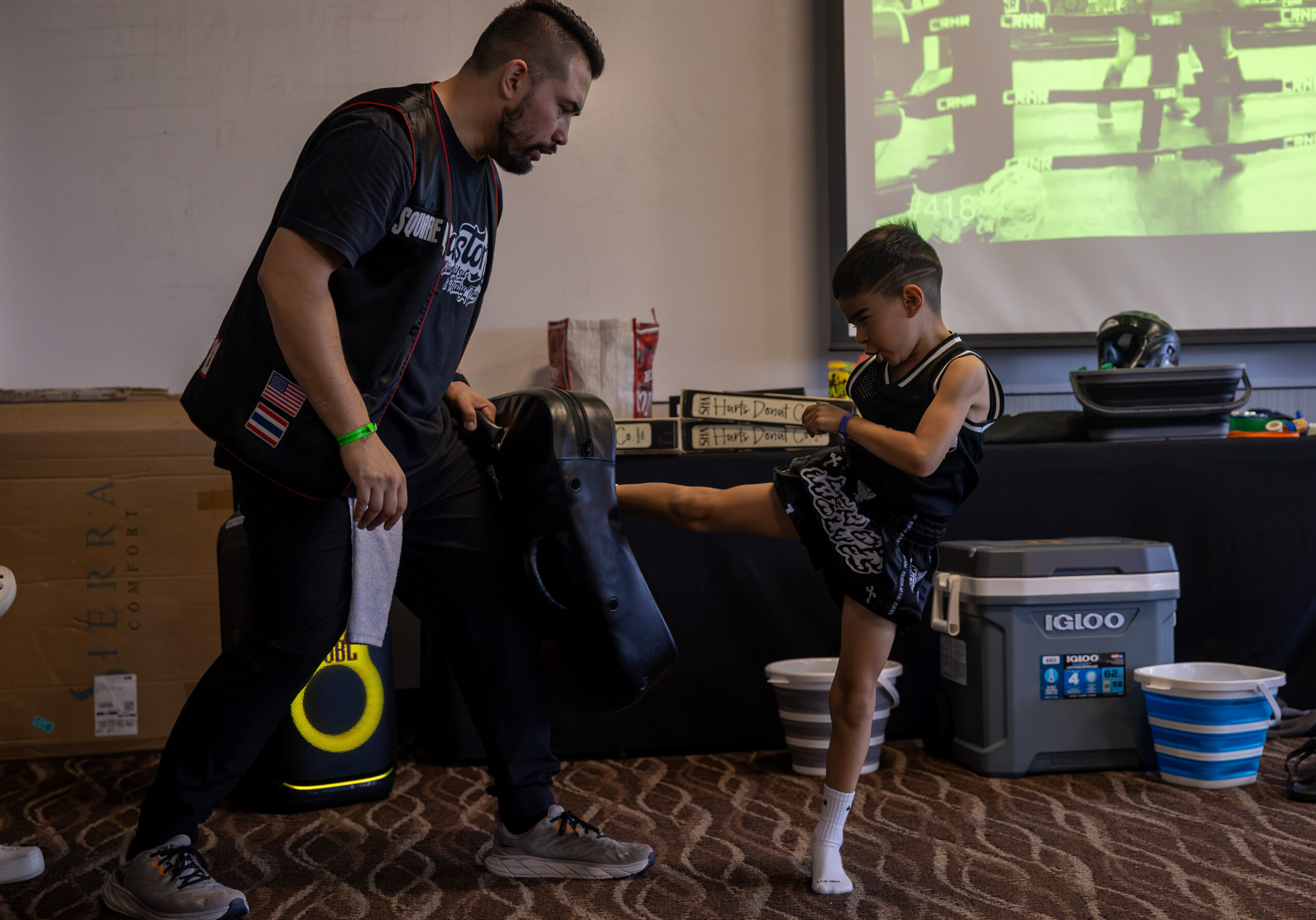 Sean Madden holding a muay thai kick shield for a child