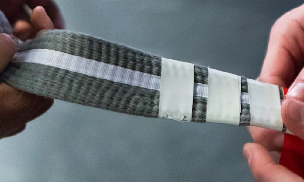 A student receives a stripe on their BJJ belt