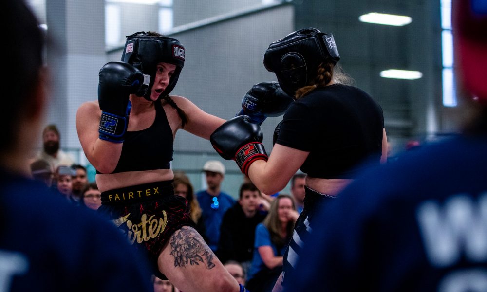 two women in headgear and boxing gloves Competing in Muay Thai