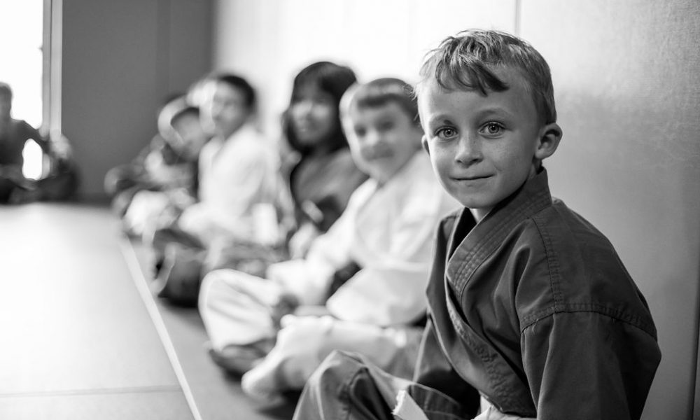 Kids smile as they sit in a line at Easton Training Center BJJ class