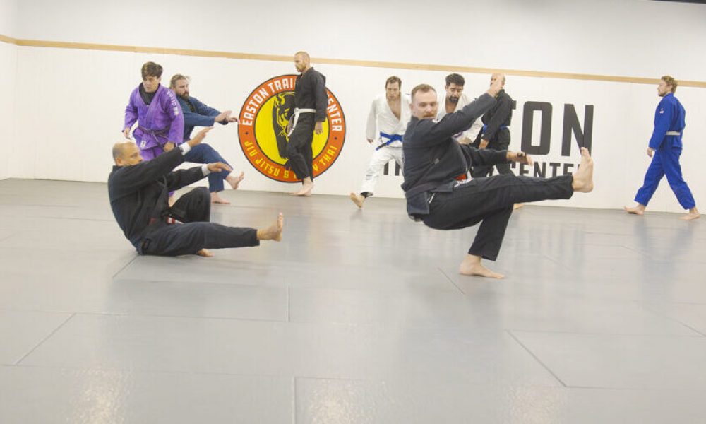 Two men in BJJ gis back break fall in a warmup