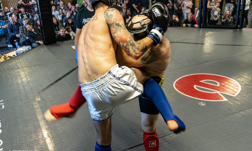 Muay Thai smoker fight. One man knees another in the stomach.