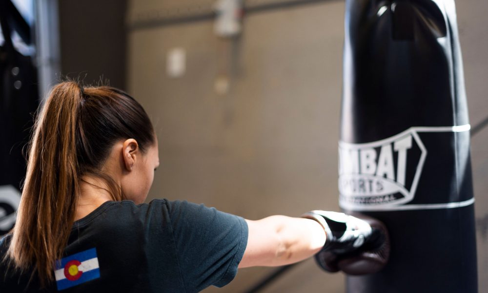 women martial arts a woman wearing boxing gloves punches a heavy bag with a right cross