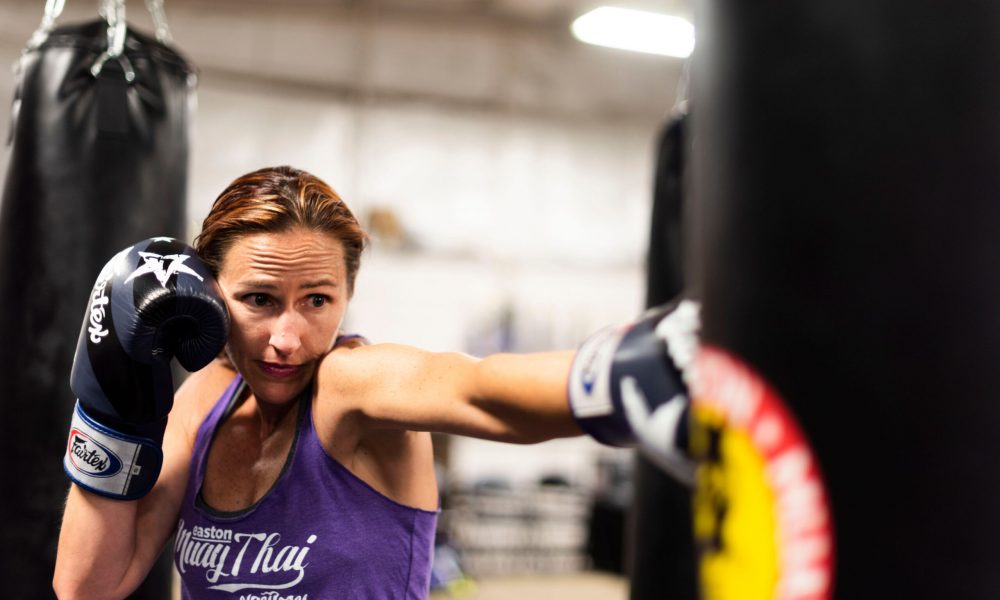 A woman punching a kickboxing heavy bag