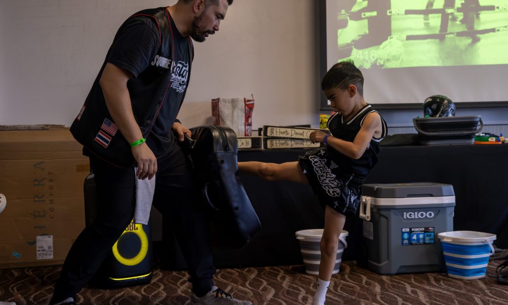 Sean Madden holding a muay thai kick shield for a child